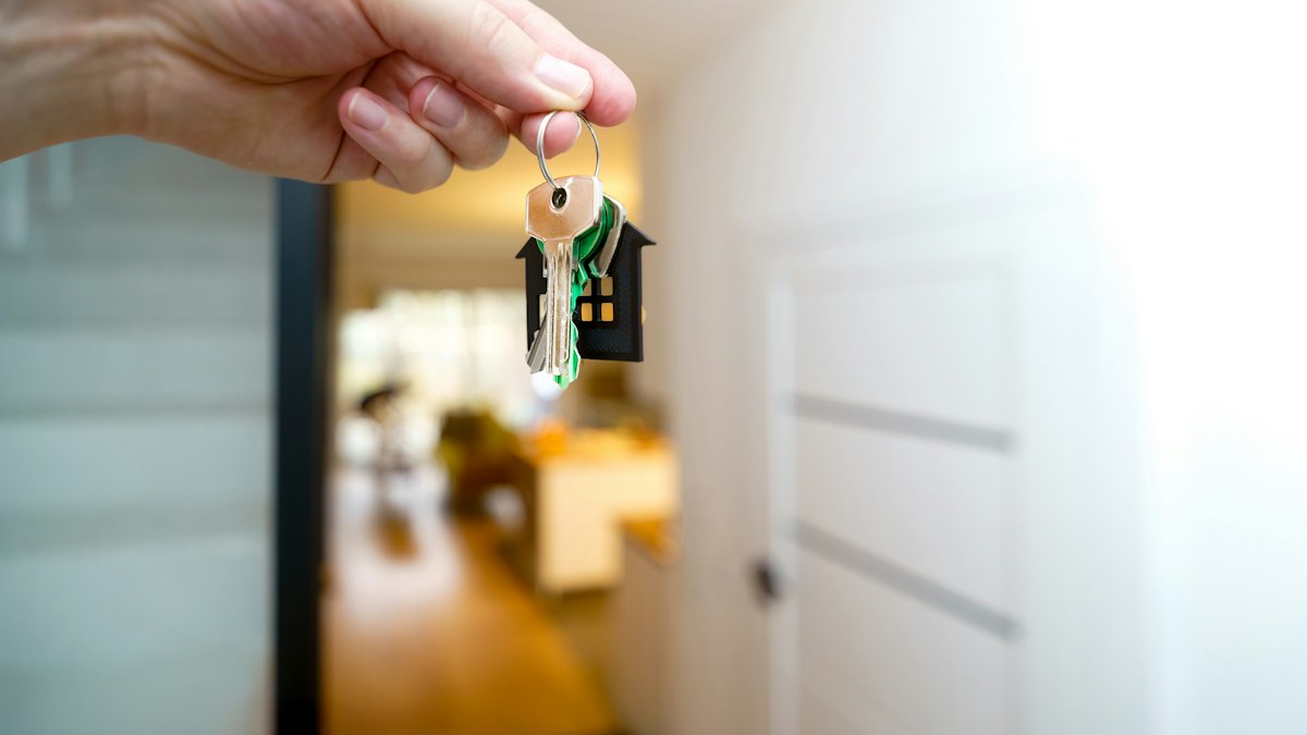 A hand holding house keys in the doorway of a new home