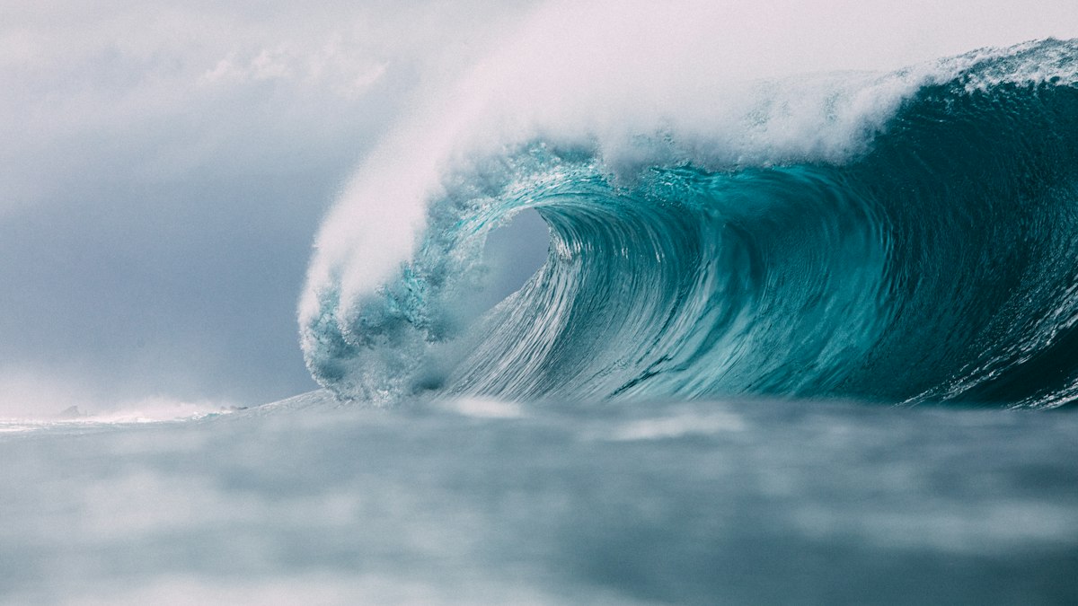 A large blue ocean wave curling just before it breaks
